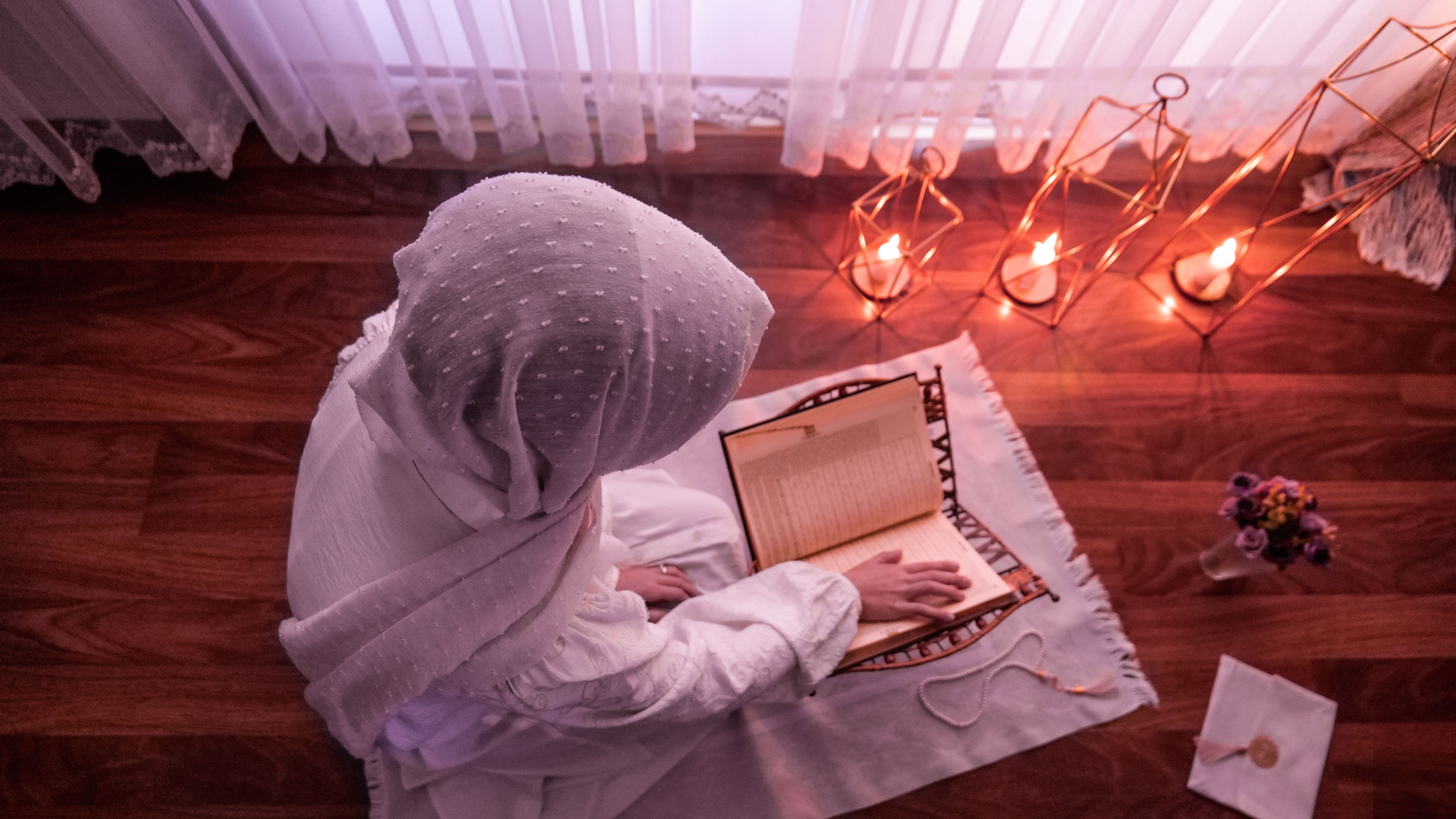 A woman reading the Quran in soft evening light